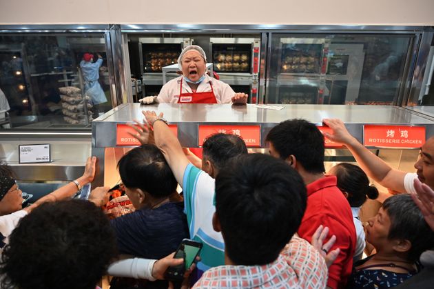People try to get a roast chicken at the first Costco outlet in China, on the stores opening day in Shanghai on August 27, 2019. - China has proved a brutal battleground for overseas food retailers in recent years, with many failing to understand consumer habits and tastes as well as local competitors building a stronger presence. (Photo by HECTOR RETAMAL / AFP)        (Photo credit should read HECTOR RETAMAL/AFP/Getty Images)