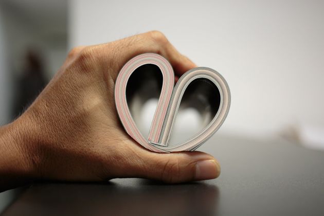 A book curved into a heart shape on man hand
