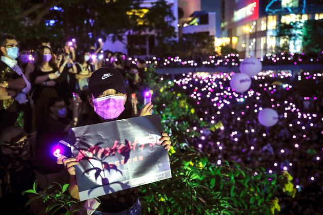 A woman holds a placard as people flash their smartphones lights during a rally at Chater Garden in Hong Kong, Wednesday, Aug. 28, 2019. Several thousand people gather at the financial district protest against what they called sexual violence by the police, as one protester said last week that she had been strip-searched unnecessarily. In another incident, a female protester's skirt became flipped up as police carried her away. Police have denied any wrongdoing in both cases. (AP Photo/Kin Cheung)