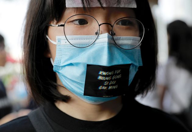 A woman wears a face mask and a sticker reading 'Add oil Hong Kong people' during a demonstration at Edinburgh Place in Hong Kong, Thursday, Aug. 22, 2019. High school students thronged a square in downtown Hong Kong Thursday to debate political reforms as residents gird for further anti-government protests. (AP Photo/Vincent Yu)