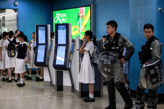 Policemen in riot gear stand guard as a group of high school students gather inside the Kowloon Tong MTR station ahead of a disruption protest in Hong Kong on September 2, 2019. - Hong Kong pro-democracy protesters threw morning rush hour train travel into chaos on September 2, kicking off another day of potential turmoil after a weekend featuring some of the worst violence in three months of anti-government protests. (Photo by Philip FONG / AFP)        (Photo credit should read PHILIP FONG/AFP/Getty Images)
