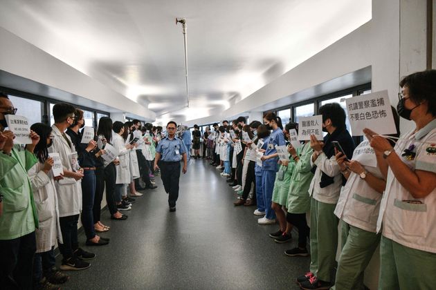Medical staff hold posters as they form a human chain to express solidarity with anti-extradition bill protesters during their lunch break at the Queen Mary Hospital in Hong Kong on September 2, 2019. - The global financial hub is in the grip of an unprecedented crisis as a largely leaderless movement has drawn millions on to the streets to protest against what they see as an erosion of freedoms and increasing interference in their affairs by Beijing. (Photo by Anthony WALLACE / AFP)        (Photo credit should read ANTHONY WALLACE/AFP/Getty Images)