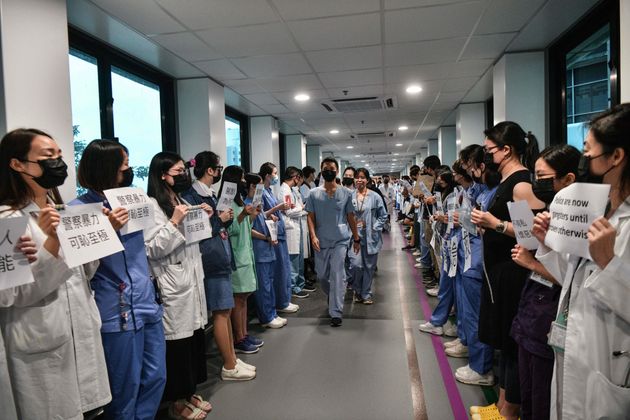 TOPSHOT - Medical staff hold posters as they form a human chain to express solidarity with anti-extradition bill protesters during their lunch break at the Queen Mary Hospital in Hong Kong on September 2, 2019. - The global financial hub is in the grip of an unprecedented crisis as a largely leaderless movement has drawn millions on to the streets to protest against what they see as an erosion of freedoms and increasing interference in their affairs by Beijing. (Photo by Anthony WALLACE / AFP)        (Photo credit should read ANTHONY WALLACE/AFP/Getty Images)