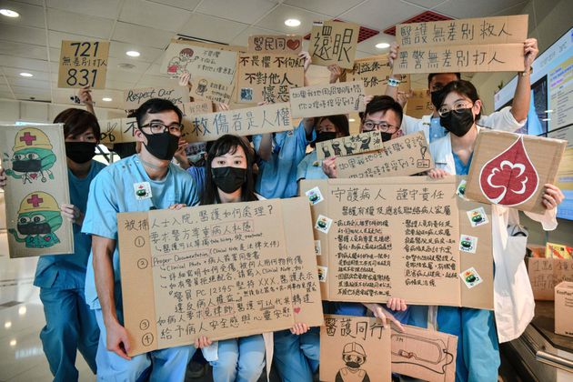 TOPSHOT - Medical staff hold placards after they formed a human chain to express solidarity with anti-extradition bill protesters during their lunch break at the Queen Mary Hospital in Hong Kong on September 2, 2019. - The global financial hub is in the grip of an unprecedented crisis as a largely leaderless movement has drawn millions on to the streets to protest against what they see as an erosion of freedoms and increasing interference in their affairs by Beijing. (Photo by Anthony WALLACE / AFP)        (Photo credit should read ANTHONY WALLACE/AFP/Getty Images)