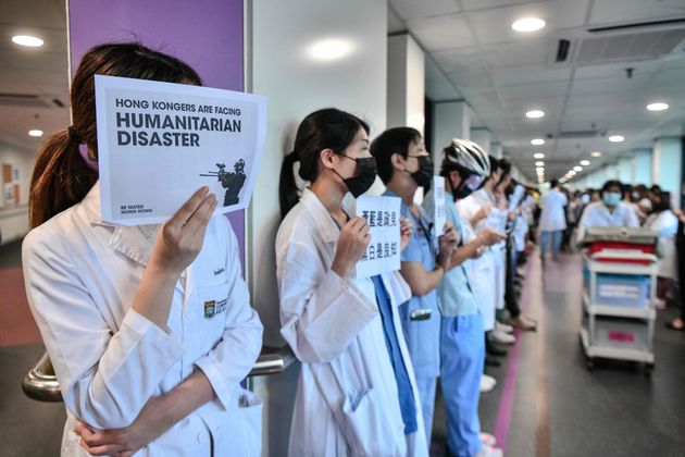 Medical staff hold posters as they form a human chain to express solidarity with anti-extradition bill protesters during their lunch break at the Queen Mary Hospital in Hong Kong on September 2, 2019. - The global financial hub is in the grip of an unprecedented crisis as a largely leaderless movement has drawn millions on to the streets to protest against what they see as an erosion of freedoms and increasing interference in their affairs by Beijing. (Photo by Anthony WALLACE / AFP)        (Photo credit should read ANTHONY WALLACE/AFP/Getty Images)