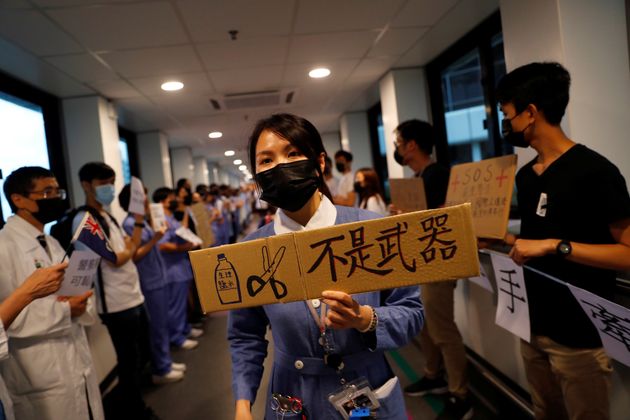 A healthcare staff holds a placard which reads ' Saline water and scissors are not weapons', as other staff members participate in a human chain to protest against the police brutality during the anti extradition bill protests, at Queen Mary Hospital, in Hong Kong, China, September 2, 2019. REUTERS/Anushree Fadnavis