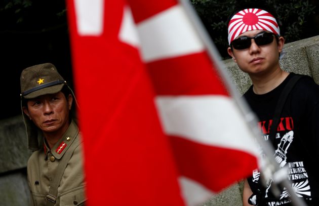 A man dressed as Japanese imperial army soldier and a man wearing a rising sun flag headband stand behind a rising sun flag in front of Yasukuni Shrine on the anniversary of Japan's surrender in World War Two in Tokyo, Japan, August 15, 2016.   REUTERS/Kim Kyung-Hoon TPX IMAGES OF THE DAY
