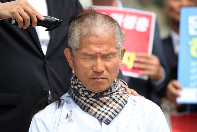 김문수 전 지사의 머리를 깎는 사람은 바리깡을 든 손만을 사용하고 있다. 바리깡을 들지 않은 손이 김 전 지사의 어깨에 얹혀져 있다.