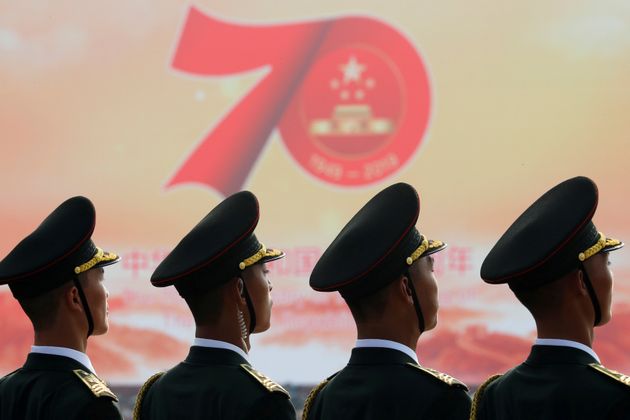 Soldiers of People's Liberation Army (PLA) are seen in front of a sign marking the 70th founding anniversary of People's Republic of China before a military parade on its National Day in Beijing, China October 1, 2019.  REUTERS/Thomas Peter     TPX IMAGES OF THE DAY