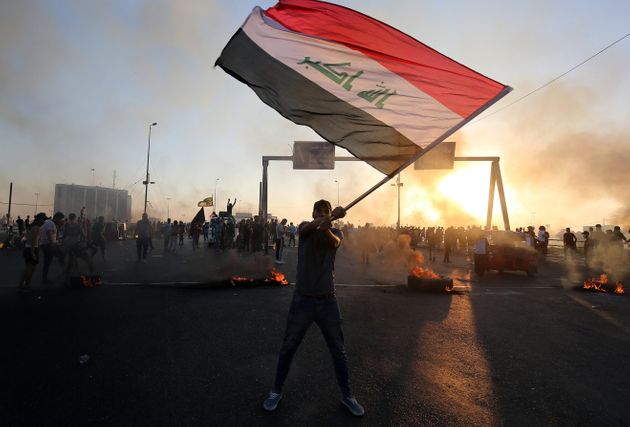 An Iraqi protester waves the national flag during a demonstration against state corruption, failing public services, and unemployment, in the Iraqi capital Baghdad on October 5, 2019. (Photo by AHMAD AL-RUBAYE/AFP via Getty Images)