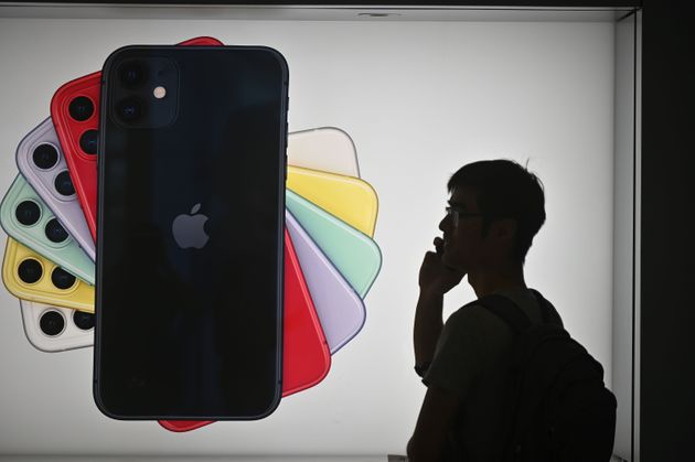 A man uses his mobile phone as he walks past advertising for the new iPhones outside the Apple store in Hong Kong on October 10, 2019. - Apple on October 10 removed an app criticised by China for allowing protestors in Hong Kong to track police, as Beijing steps up pressure on foreign companies deemed to be providing support to the pro-democracy movement. (Photo by Philip FONG / AFP) (Photo by PHILIP FONG/AFP via Getty Images)