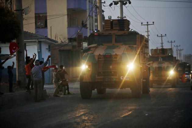 Shortly after the Turkish operation inside Syria had started, local residents cheer and applaud as a convoy of Turkish forces vehicles is driven through the town of Akcakale, Sanliurfa province, southeastern Turkey, at the border between Turkey and Syria, Wednesday, Oct. 9, 2019. Turkey launched a military operation Wednesday against Kurdish fighters in northeastern Syria after U.S. forces pulled back from the area, with a series of airstrikes hitting a town on Syria's northern border. (AP Photo/Lefteris Pitarakis)