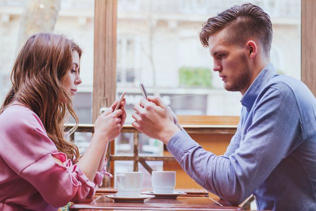 always connected, internet addiction, young couple in cafe looking at their smartphones, social network concept