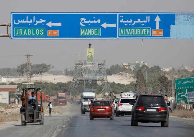 Cars pass under a road sign that shows the direction to Manbij city, at the entrance of Manbij, Syria October 15, 2019. REUTERS/Omar Sanadiki