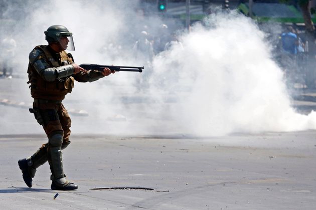 A police officer fires rubber pellets at protesters as a state of emergency remains in effect in Santiago, Chile, Sunday, Oct. 20, 2019. Protests in the country have spilled over into a new day, even after President Sebastian Pinera cancelled the subway fare hike that prompted massive and violent demonstrations. (AP Photo/Luis Hidalgo)