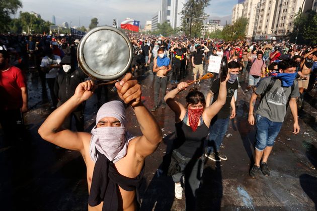 SANTIAGO, CHILE - OCTOBER 21: Demonstrators shouts slogans and display banners during a protest against Presidente Sebastian Piñera on October 21, 2019 in Santiago, Chile. President Sebastian Piñera suspended the 3.5% subway fare hike and declared the state of emergency for the first time since the return of democracy in 1990. Protests had begun on Friday and developed into looting and arson, generating chaos in Santiago, Valparaiso and a dozen other cities resulting in at least 8 dead.  (Photo by Marcelo Hernandez/Getty Images)