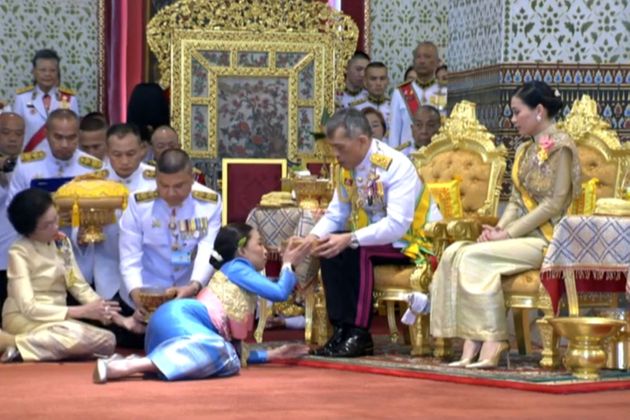 This screengrab from Thai TV Pool video taken on May 5, 2019 shows Thailand's King Maha Vajiralongkorn anointing his daughter Princess Bajrakitiyabha Mahidol while Queen Suthida looks on during a ceremony at the Grand Palace in Bangkok. - Thai King Maha Vajiralongkorn was crowned on May 4 with a golden-tiered headpiece, the highlight of an elaborate three-day coronation ceremony two years after he ascended the throne. (Photo by THAI TV POOL / THAI TV POOL / AFP) / 