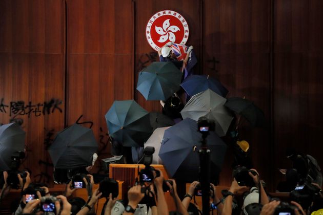 FILE - In this July 1, 2019, file photo, a protester covers the Hong Kong emblem with a Hong Kong colonial flag after they broke into the Legislative Council building in Hong Kong. Hong Kong authorities on Wednesday, Oct. 23, 2019 withdrew an unpopular extradition bill that sparked months of chaotic protests that have since morphed into a campaign for greater democratic change. (AP Photo/Kin Cheung, File)
