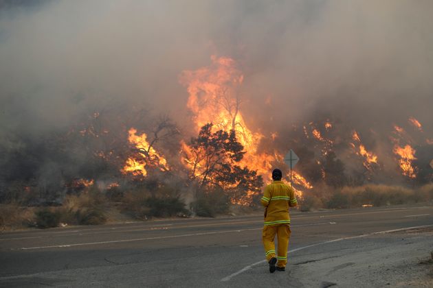 A member of the news media watches flames from a wildfire along Sierra Highway Thursday, Oct. 24, 2019, in Santa Clarita, Calif. (AP Photo/Marcio Jose Sanchez)