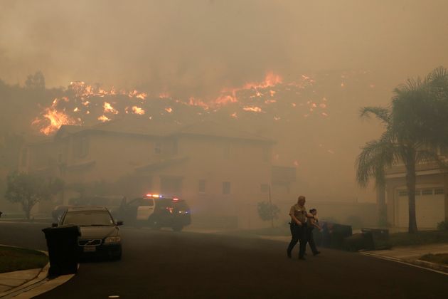 Police walk along a street as they try to evacuate residents as a wildfire approaches Thursday, Oct. 24, 2019, in Santa Clarita, Calif. (AP Photo/Marcio Jose Sanchez)