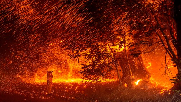 A photographer takes photos amidst a shower of embers as wind and flames rip through the area during the Kincade fire near Geyserville, California on October 24, 2019. - fast-moving wildfire roared through California wine country early Thursday, as authorities warned of the imminent danger of more fires across much of the Golden State. The Kincade fire in Sonoma County kicked up Wednesday night, quickly growing from a blaze of a few hundred acres into an uncontained 10,000-acre (4,000-hectare) inferno, California fire and law enforcement officials said. (Photo by Josh Edelson / AFP) (Photo by JOSH EDELSON/AFP via Getty Images)