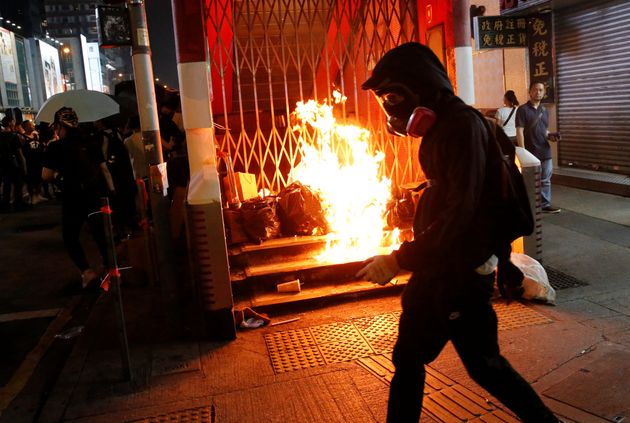 An anti-government protester walks past a burning barrier outside Mong Kok MTR station during a protest in Hong Kong, China October 27, 2019. REUTERS/Tyrone Siu