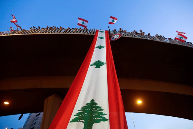 Demonstrators stand on a bridge decorated with a national flag during an anti-government protest along a highway in Jal el-Dib, Lebanon October 21, 2019. REUTERS/Mohamed Azakir     TPX IMAGES OF THE DAY