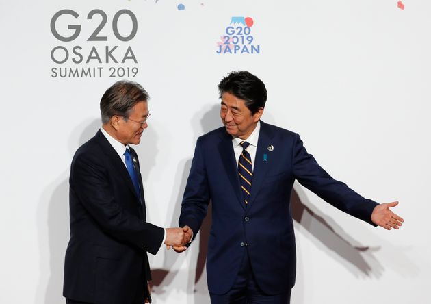 South Korean President Moon Jae-in, left, is welcomed by Japanese Prime Minister Shinzo Abe upon his arrival for an welcome and family photo session at G-20 leaders summit in Osaka, Japan, June 28, 2019. (Kim Kyung-Hoon/Pool Photo via AP)