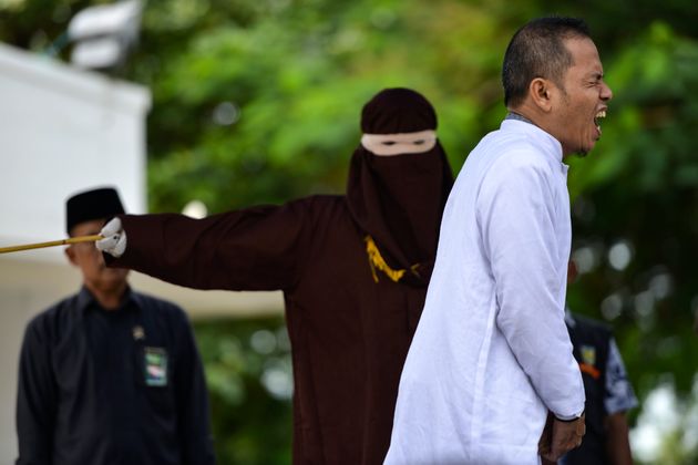 Aceh Ulema Council (MPU) member Mukhlis reacts as he is whipped in public by a member of the Sharia police in Banda Aceh on October 31, 2019. - An Indonesian man working for an organisation which helped draft strict religious laws ordering adulterers to be flogged was himself publically whipped on October 31 after he was caught having an affair with a married woman. (Photo by CHAIDEER MAHYUDDIN / AFP) (Photo by CHAIDEER MAHYUDDIN/AFP via Getty Images)