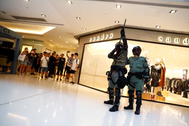 A police officer aims his weapon as shoppers and anti-government protesters gather at New Town Plaza in Sha Tin, Hong Kong, China November 3, 2019. REUTERS/Thomas Peter