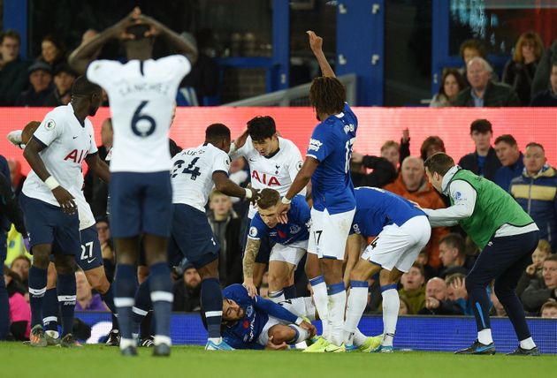 Teammates comfort Everton's Portuguese midfielder André Gomes (C floor) as he gets attention for an injury as Everton's Irish defender Seamus Coleman (R) looks on during the English Premier League football match between Everton and Tottenham Hotspur at Goodison Park in Liverpool, north west England on November 3, 2019. (Photo by Oli SCARFF / AFP) / RESTRICTED TO EDITORIAL USE. No use with unauthorized audio, video, data, fixture lists, club/league logos or 'live' services. Online in-match use limited to 120 images. An additional 40 images may be used in extra time. No video emulation. Social media in-match use limited to 120 images. An additional 40 images may be used in extra time. No use in betting publications, games or single club/league/player publications. /  (Photo by OLI SCARFF/AFP via Getty Images)