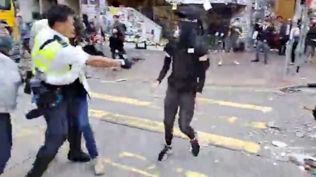 In this image made from video, a police officer, left, prepares to shoot a protester, center, in Hong Kong Monday, Nov. 11, 2019. The police shot the protester as demonstrators blocked subway lines and roads during the Monday morning commute. (Cupid Producer via AP)
