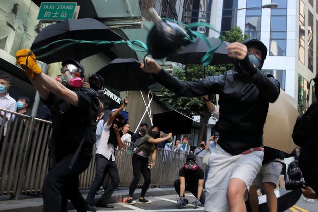 Protesters use a sling shot to launch a milk drink container towards riot police during protests in the Central district of Hong Kong, Monday, Nov. 11, 2019. A protester was shot by police Monday in a dramatic scene caught on video as demonstrators blocked train lines and roads in a day of spiraling violence fueled by demands for democratic reforms. (AP Photo/Kin Cheung)