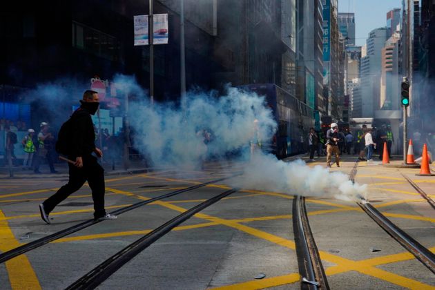 A protester approaches a gas canister deployed in Central district of Hong Kong on Monday, Nov. 11, 2019. A protester was shot by police Monday in a dramatic scene caught on video as demonstrators blocked train lines and roads during the morning commute. (AP Photo/Vincent Yu)