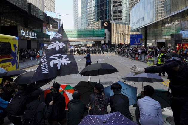 Protesters with umbrellas face off riot police in Hong Kong on Monday, Nov. 11, 2019. A protester was shot by police Monday in a dramatic scene caught on video as demonstrators blocked train lines and roads during the morning commute. (AP Photo/Vincent Yu)