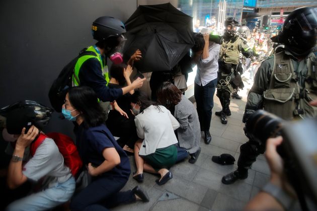 A crowd tries to take cover from pepper spray in Hong Kong on Monday, Nov. 11, 2019. A  protester was shot by police Monday in a dramatic scene caught on video as demonstrators blocked train lines and roads during the morning commute. (AP Photo/Kin Cheung)