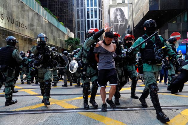 A protester, center, is detained in Central district of Hong Kong on Monday, Nov. 11, 2019. A Hong Kong protester was shot by police Monday in a dramatic scene caught on video as demonstrators blocked train lines and roads during the morning commute. (AP Photo/Vincent Yu)