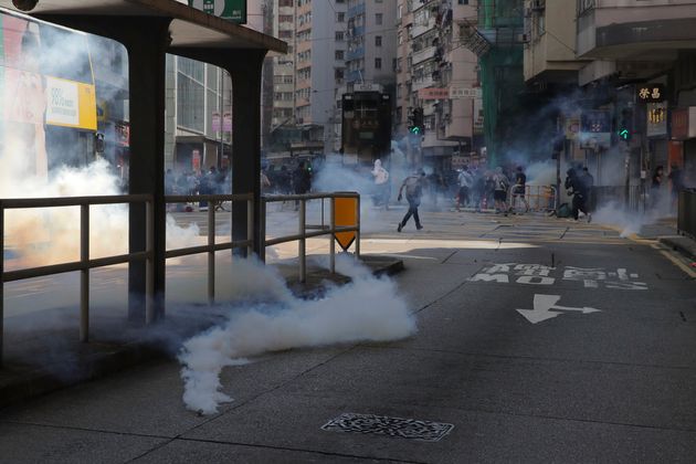 Tear gas fills the streets of Hong Kong Monday, Nov. 11, 2019. Police in Hong Kong have shot a protester as demonstrators blocked subway lines and roads during the morning commute. (AP Photo/Kin Cheung)