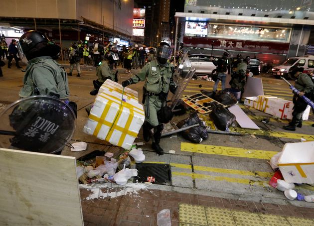 Riot police officers clear up a road from barricade set up by protesters in Mong Kok, Hong Kong, Sunday, Nov. 10, 2019. Police fired tear gas and protesters broke windows at a shopping mall Sunday in anti-government demonstrations across Hong Kong amid anger over a student activist's death and the arrest of pro-democracy lawmakers. (AP Photo/Dita Alangkara)