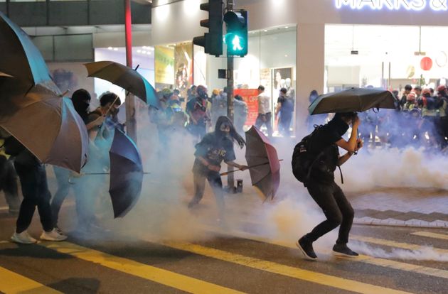 Protesters use umbrellas to protect themselves as they face police teargas in Hong Kong, Sunday, Nov. 10, 2019. Protesters smashed windows in a subway station and a shopping mall Sunday and police made arrests in areas across Hong Kong amid anger over a demonstrator's death and the arrest of pro-democracy lawmakers.Hong Kong is in the sixth month of protests that began in June over a proposed extradition law and have expanded to include demands for greater democracy and other grievances. (AP Photo/Kin Cheung)