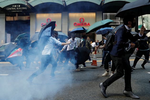 Office workers run away from tear gas as they attend a flash mob anti-government protest at the financial Central district in Hong Kong, China, November 11, 2019. REUTERS/Tyrone Siu