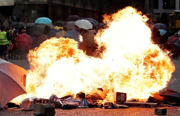 Demonstrators carry umbrellas behind a fire during an anti-government protest in Central, Hong Kong, China November 12, 2019.  REUTERS/Shannon Stapleton