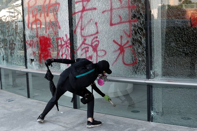 A protester breaks a glass wall sprayed with graffiti at Hong Kong Polytechnic University in Hong Kong, China November 11, 2019. REUTERS/Shannon Stapleton
