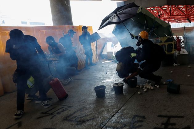 Smoke is seen as protesters shield with an umbrella at Hong Kong Polytechnic University in Hong Kong, China November 11, 2019. REUTERS/Shannon Stapleton