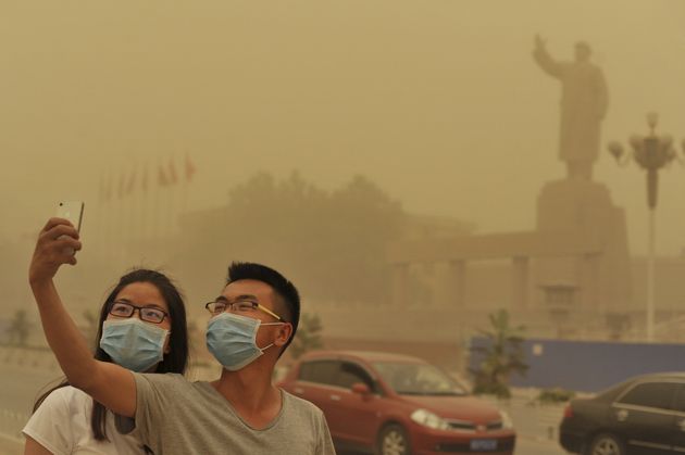 Residents wearing masks pose for a photograph near a statue of late Chinese Chairman Mao Zedong, as a sandstorm hits Kashgar, Xinjiang Uighur Autonomous Region, China, May 10, 2015. Picture taken May 10, 2015. REUTERS/Stringer TPX IMAGES OF THE DAY    CHINA OUT. NO COMMERCIAL OR EDITORIAL SALES IN CHINA