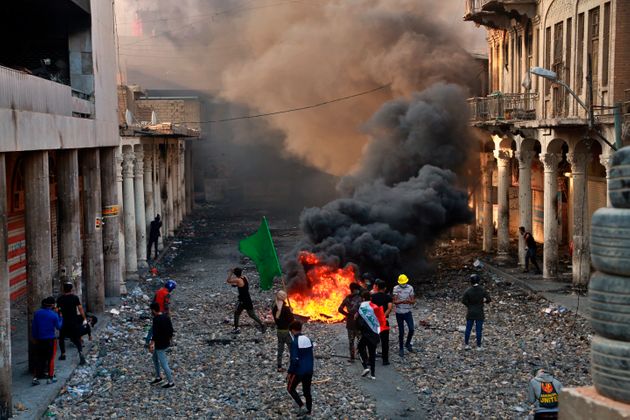Anti-government protesters set fire while security forces close Rasheed Street during clashes in Baghdad, Iraq, Thursday, Nov. 28, 2019. Scores of protesters have been shot dead in the last 24 hours, amid spiraling violence in Baghdad and southern Iraq, officials said. (AP Photo/Khalid Mohammed)