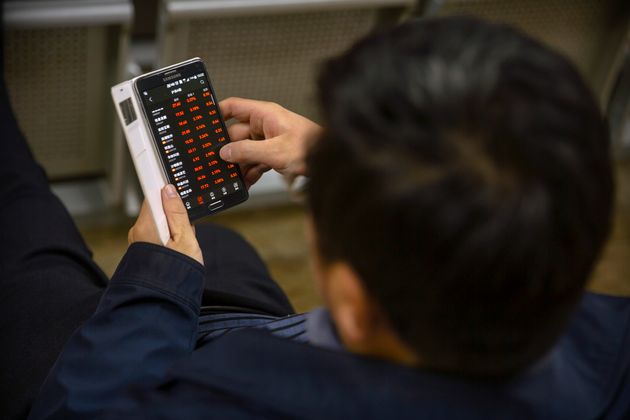A Chinese investor uses a smartphone as he monitors stock prices at a brokerage house in Beijing, Monday, Nov. 4, 2019. Asian stock markets followed Wall Street higher Monday after unexpectedly strong U.S. jobs data helped to soothe worries American factory activity was weaker than forecast. (AP Photo/Mark Schiefelbein)