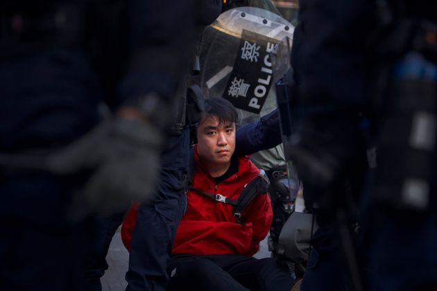 A pro-democracy protester is detained by policemen during a rally in Hong Kong, Sunday, Dec. 1, 2019. A huge crowd took to the streets of Hong Kong on Sunday, some driven back by tear gas, to demand more democracy and an investigation into the use of force to crack down on the six-month-long anti-government demonstrations. (AP Photo/Ng Han Guan)