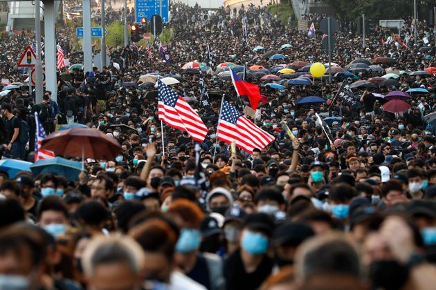 Pro-democracy protesters flood a street during a rally in Hong Kong, Sunday, Dec. 1, 2019. A huge crowd took to the streets of Hong Kong on Sunday, some driven back by tear gas, to demand more democracy and an investigation into the use of force to crack down on the six-month-long anti-government demonstrations. (AP Photo/Vincent Thian)