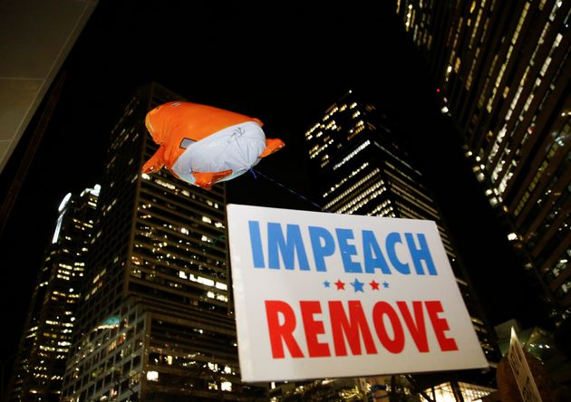 A balloon depicting U.S. President Donald Trump as a baby flies over a sign calling for his impeachment and removal during a rally outside the federal building in Seattle, Washington, U.S. December 17, 2019.  REUTERS/Lindsey Wasson